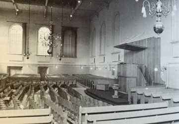 <p>Vlak nadat zij de Plantagekerk kochten, liet de vrijgemaakte kerkeraad onderhoudswerkzaamheden uitvoeren. In het interieur veranderde de opstelling rond de preekstoel. De oude kansel werd vervangen door een nieuw exemplaar, het doophek verdween en voor de preekstoel werden de stoelen anders opgesteld. Foto van het interieur uit 1954, waarop ook de nieuwe brede (nood)uitgang te zien is (Meijering en Veldhuizen 1994, 30). </p>
